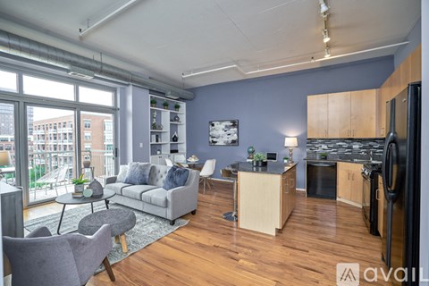 A kitchen and living room with a grey couch and a grey chair.