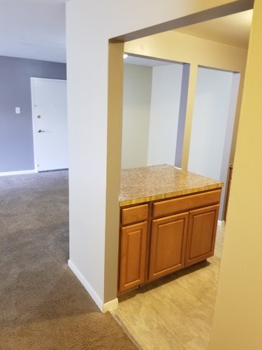 A kitchen with a granite counter top and wooden cabinets.