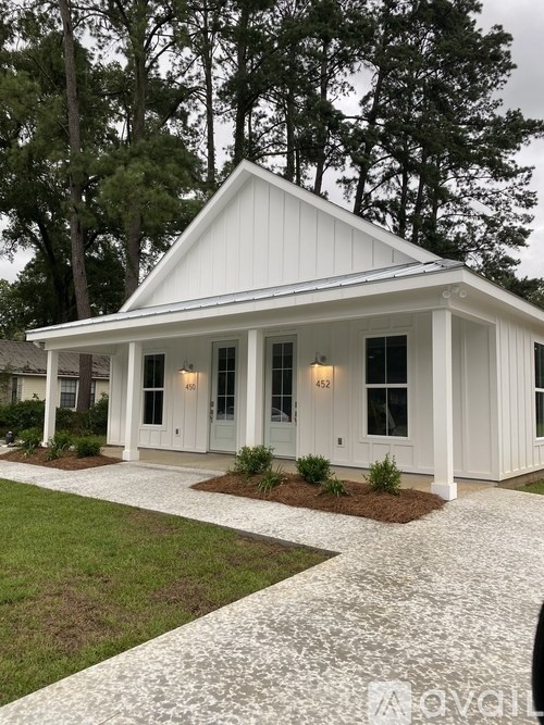 A white house with a grey roof and a white walkway in front.