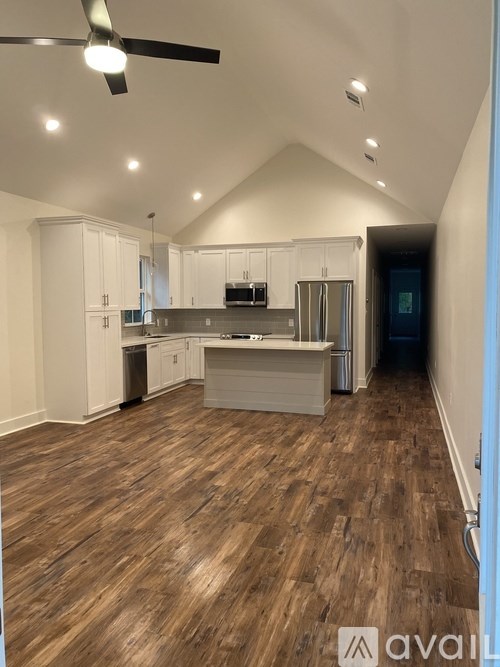 A spacious kitchen with wooden flooring and white cabinetry.