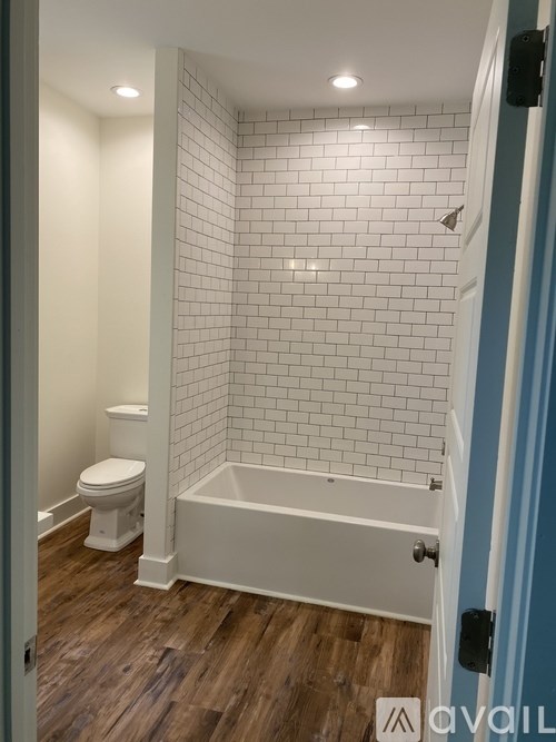 A white tiled bathroom with a toilet and a bathtub.