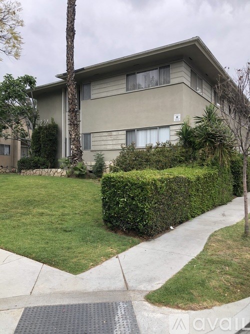 A beige apartment building with a green lawn in front.