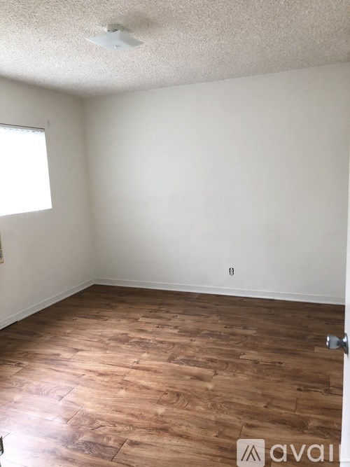 A room with wooden flooring and a window letting in light.
