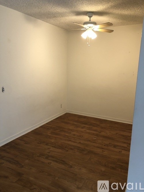 A room with a ceiling fan and wooden flooring.