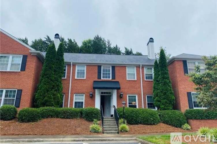 A red brick house with a black front door and steps leading up to it.