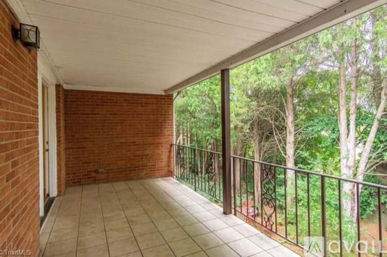 A balcony with a brick wall and tiled floor.