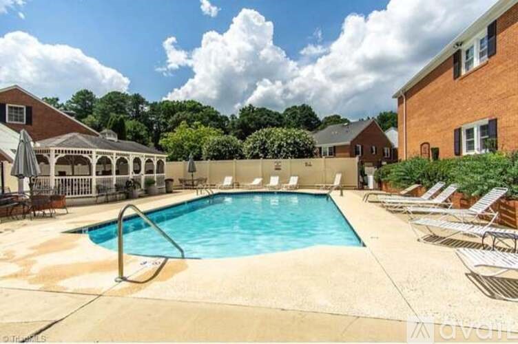 A pool surrounded by lounge chairs and a building in the background.