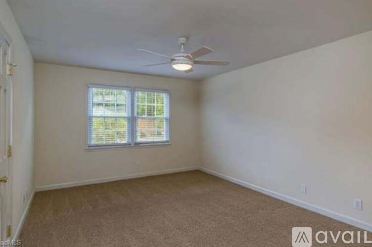 A room with a ceiling fan and a window with blinds.