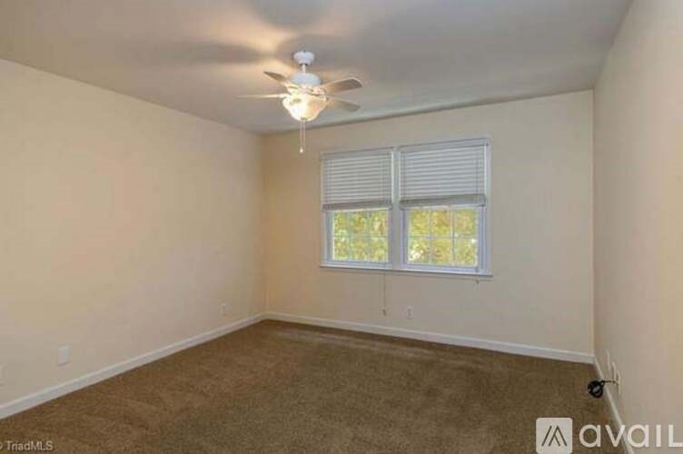 A room with a ceiling fan and a window with blinds.