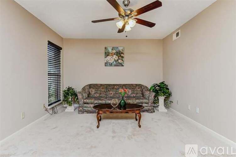 A living room with a couch, a coffee table, and a ceiling fan.