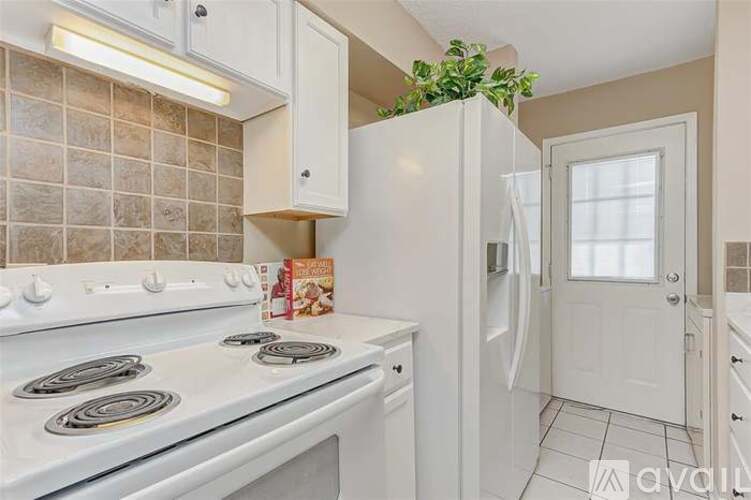 A kitchen with a white stove top oven and white cabinets.