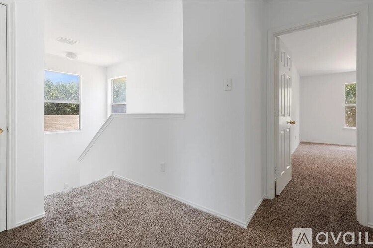 A room with white walls and carpeted floor with a window on the left side.