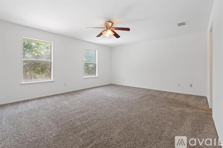 A room with a ceiling fan and carpeted floor.
