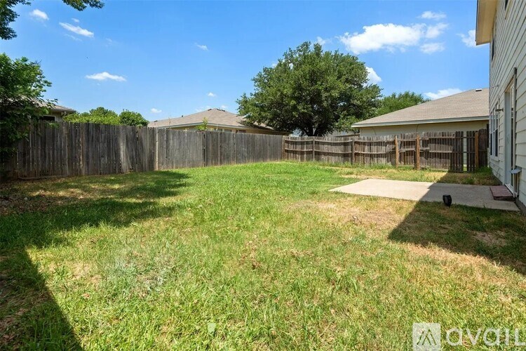 A backyard with a wooden fence and a house in the background.