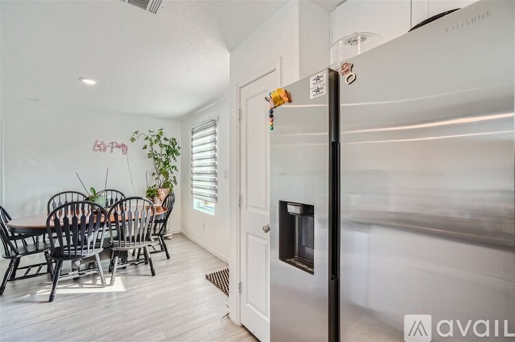 A kitchen with a white fridge and a dining table with chairs.