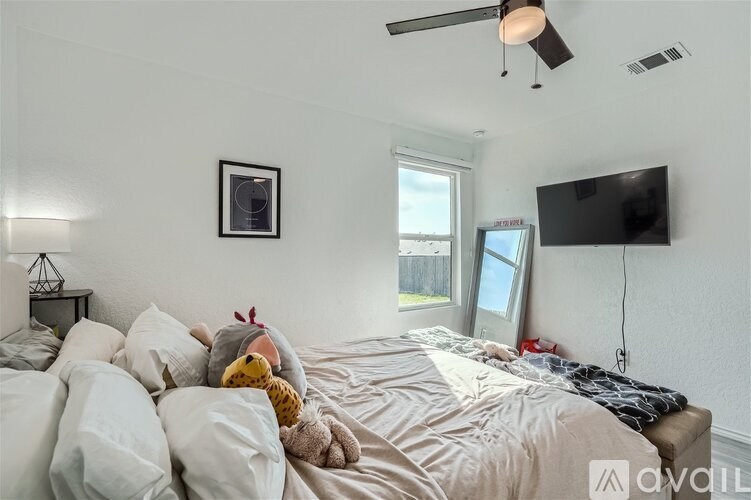 A bedroom with a bed, a ceiling fan, and a window.