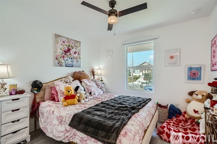 A bedroom with a bed, a dresser, a ceiling fan, and a window.