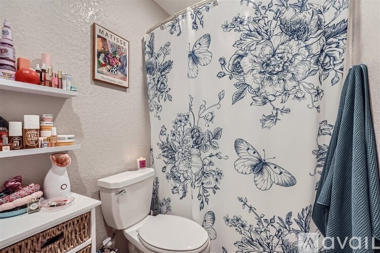 A bathroom with a floral shower curtain and a white toilet.