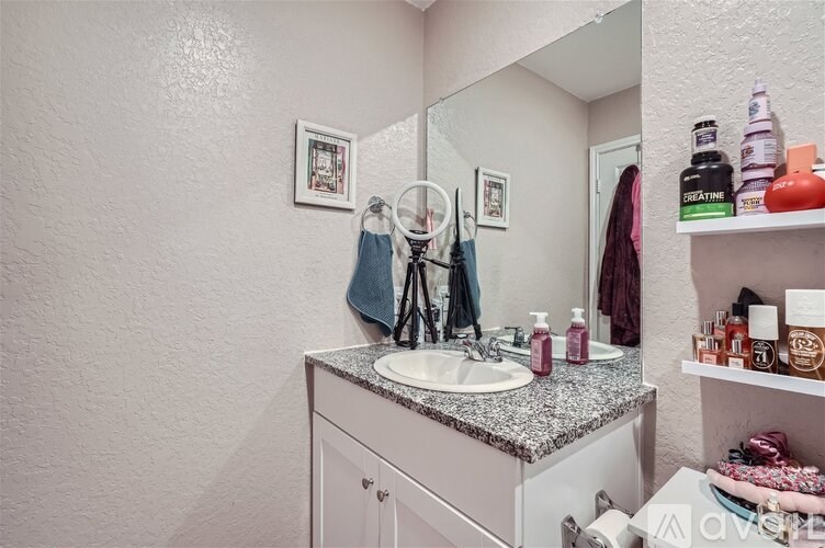 A bathroom with a sink, mirror, and toiletries.