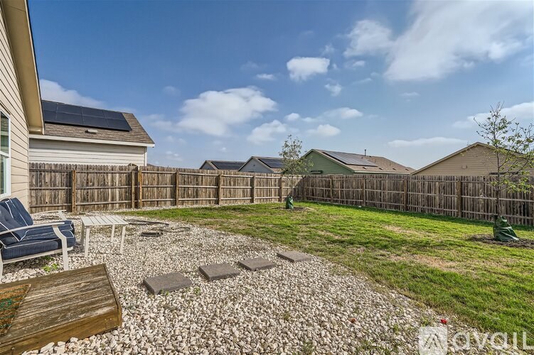 A backyard with a gravel patio and a wooden deck.