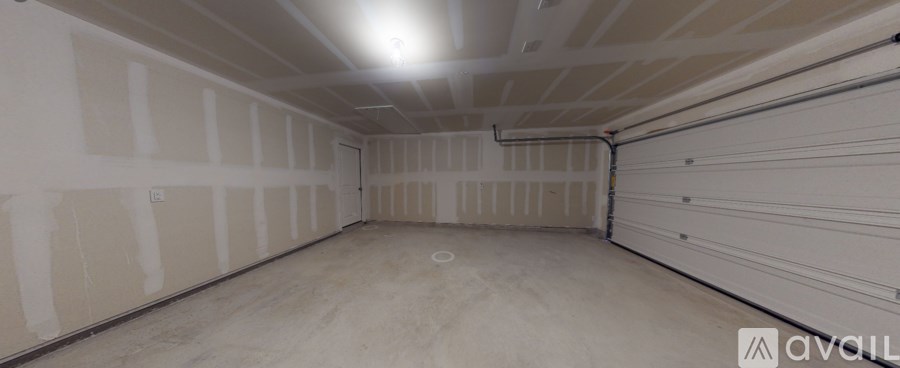 A spacious garage with a concrete floor and walls covered in drywall.