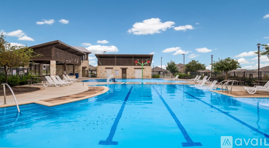 A large outdoor swimming pool with lounge chairs and a building in the background.