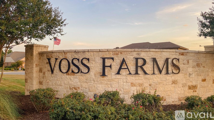 Voss Farms sign on a stone wall with an American flag in the background.