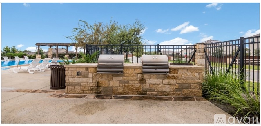 A pool area with a stone wall and a black fence.