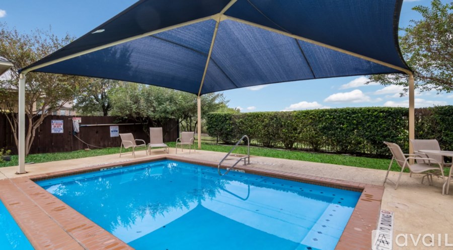 A pool with a blue umbrella and chairs around it.
