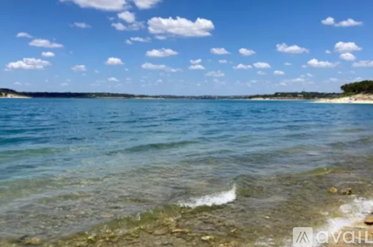 A beach with clear water and a partly cloudy sky.
