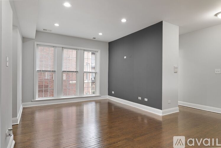 A spacious room with wooden floors and a large window.