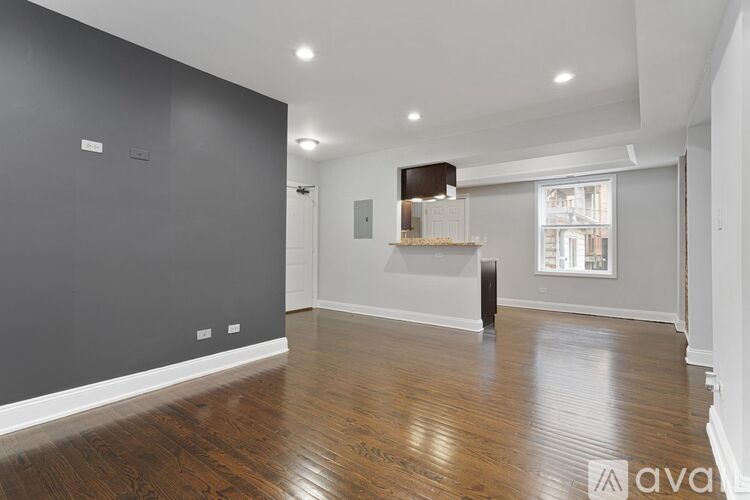 A spacious room with wooden flooring and a large window.