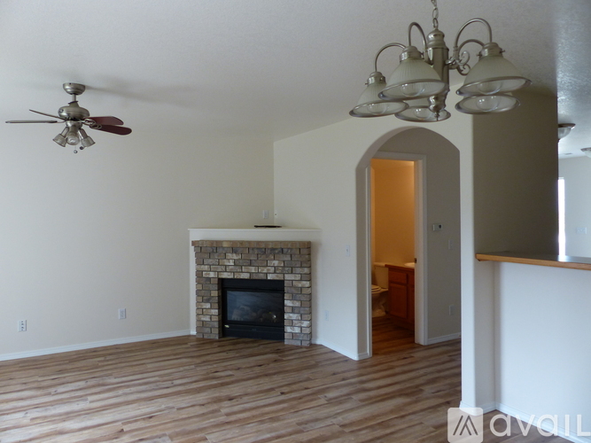 A living room with a fireplace and a ceiling fan.