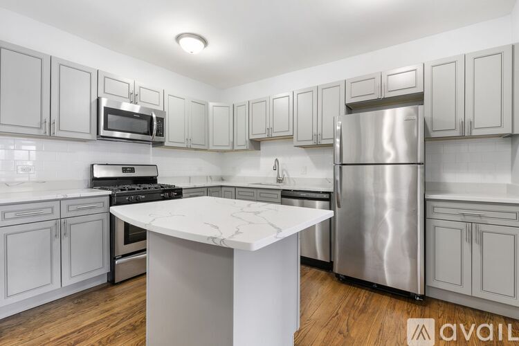 A kitchen with a white island and stainless steel appliances.