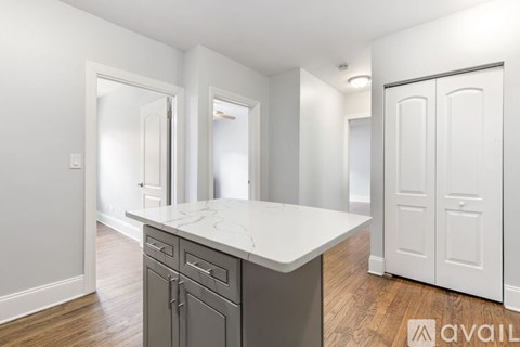 A kitchen with a marble countertop and wooden flooring.