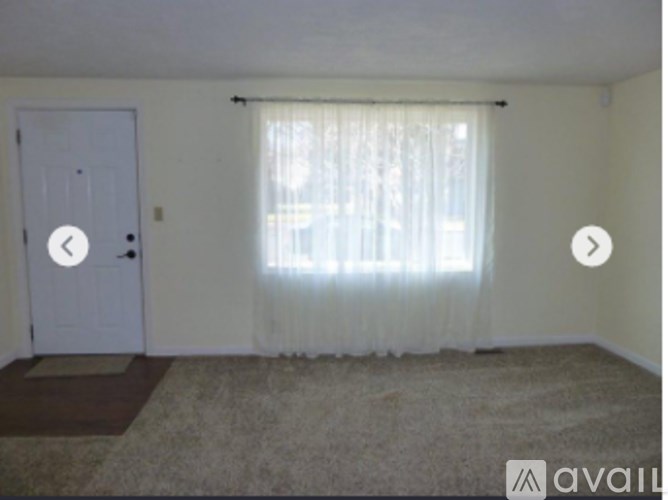 A room with a white door and a window with curtains.