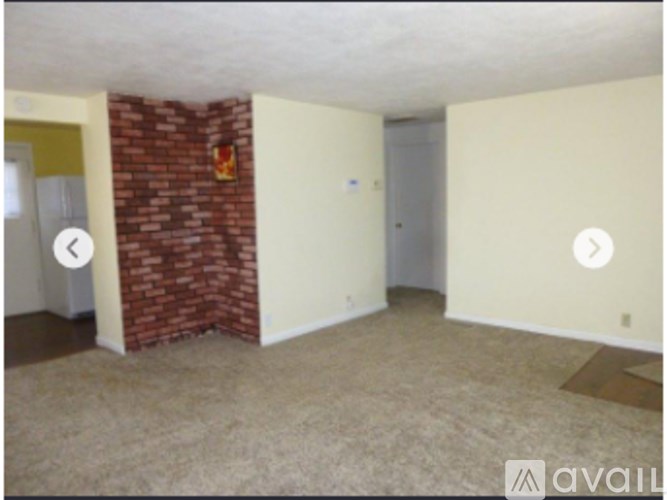 A room with a brick fireplace and carpeted floor.