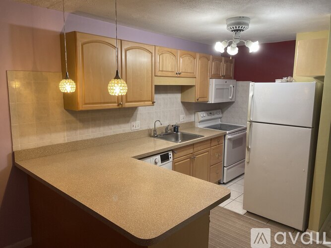A kitchen with a white refrigerator and wooden cabinets.