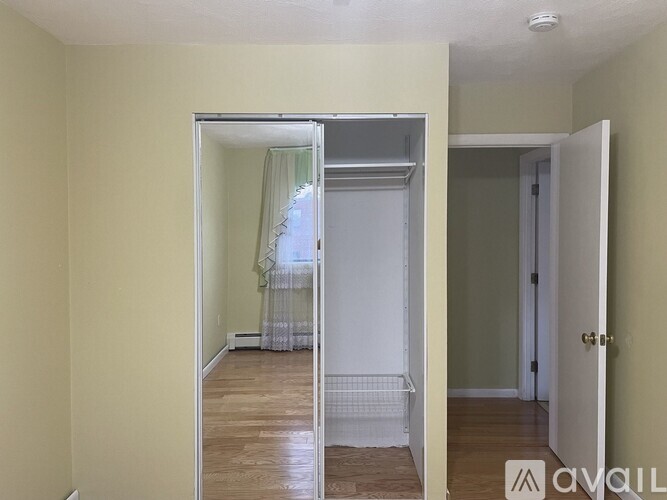 A room with a white door and a mirror showing a bedroom.