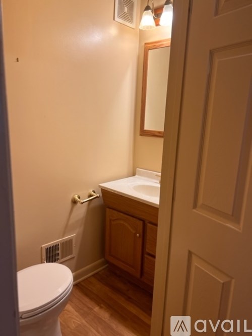 A bathroom with a toilet, sink and mirror.