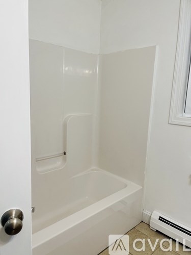 A white bathroom with a tub and a door.
