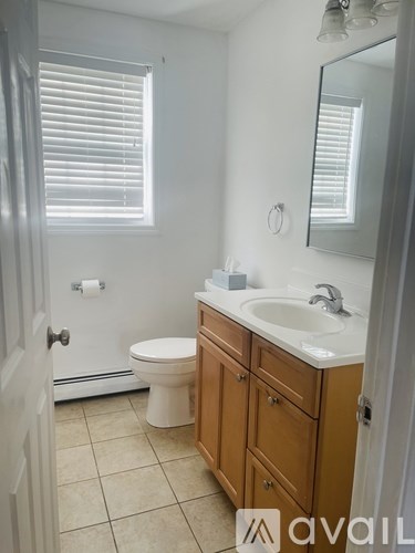 A bathroom with a toilet, sink, and mirror.
