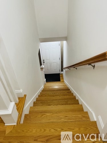 A wooden staircase with white walls and a white door at the top.