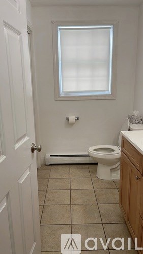 A bathroom with a toilet, sink, and window.
