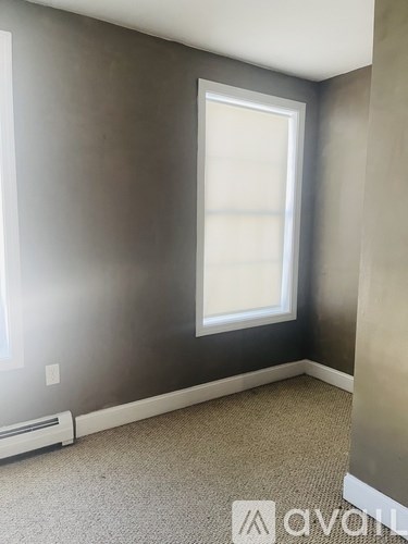 A room with a window and a carpeted floor.