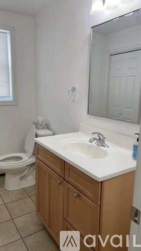 A bathroom with a toilet, sink, and mirror.
