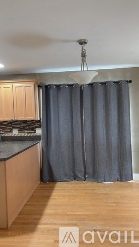 A kitchen with wooden floors and a grey curtain.