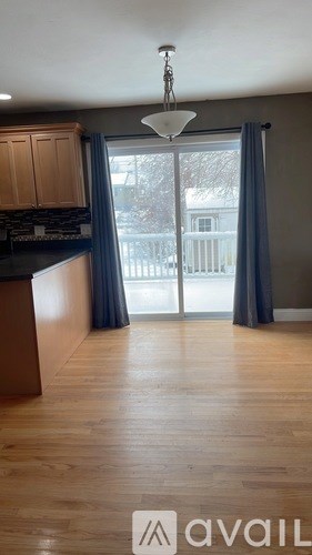 A kitchen with wooden floors and a large window with curtains.
