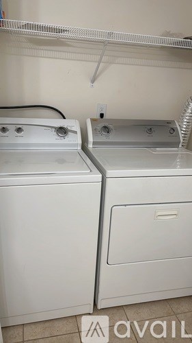 Two white front loading washing machines in a laundry room.