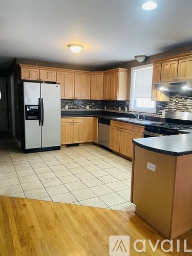 A kitchen with wooden cabinets and a black fridge.